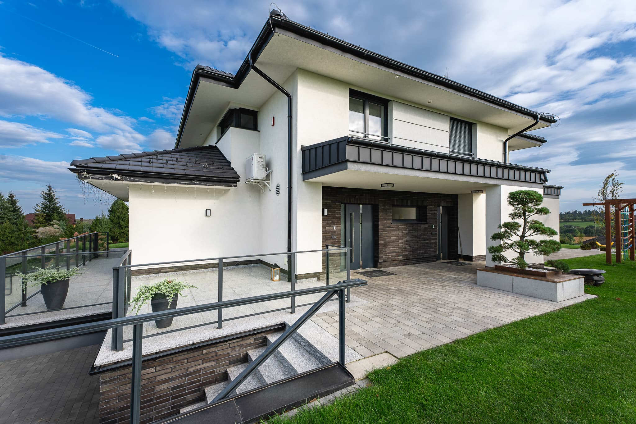 Nowoczesny biały dom jednorodzinny z czarnym dachem i oknami Pagen