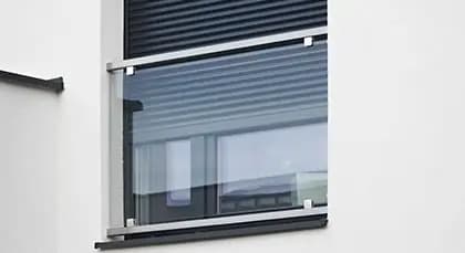 Żaluzje fasadowe o lamelach w kolorze szarym, zamontowane na nowoczesnym budynku